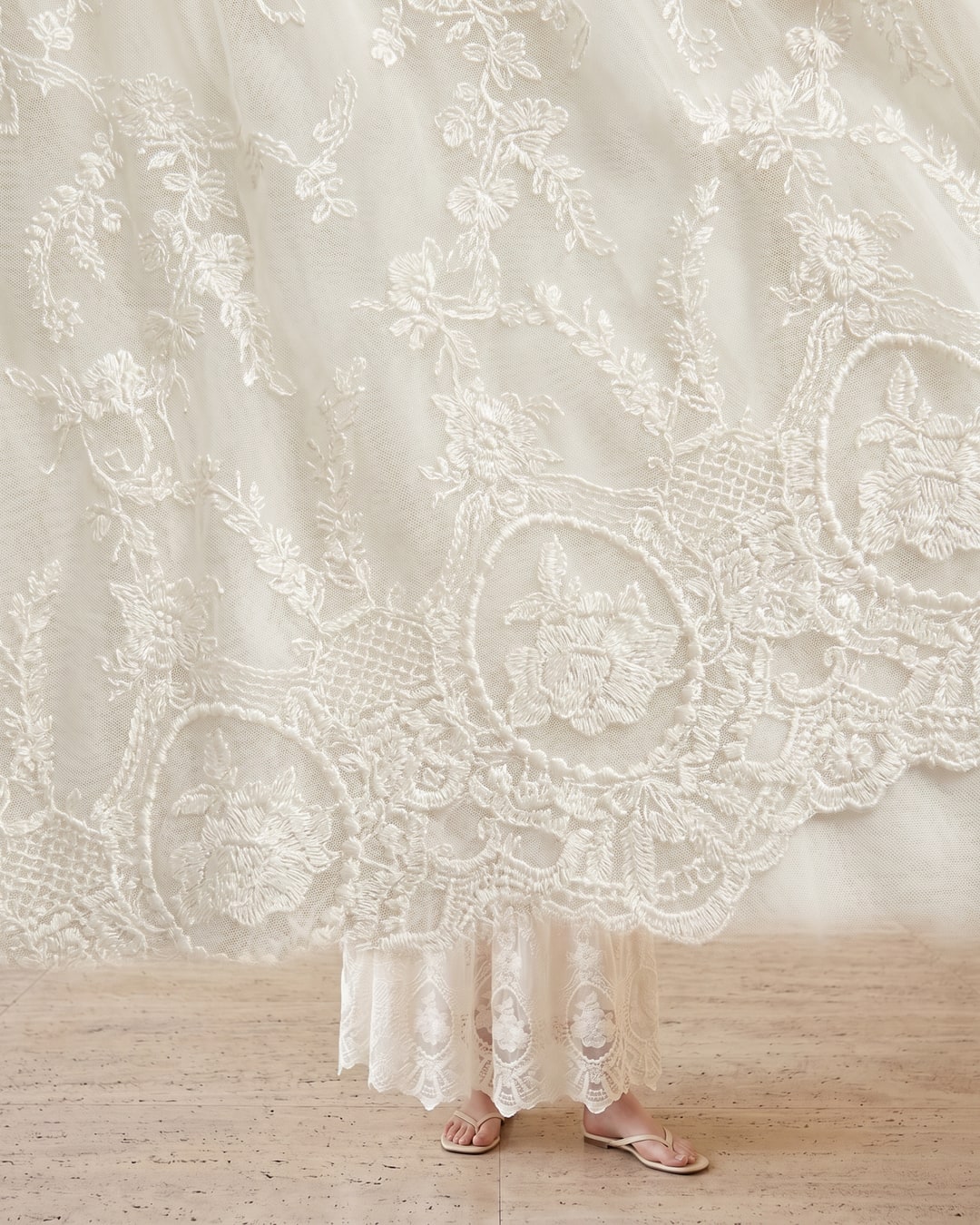 Macro detail of the Aemilia floral-embroidered lace chiffon in Avorio with its shirred tie waistband and scalloped-lace edge for Hugo Caesar Tassi