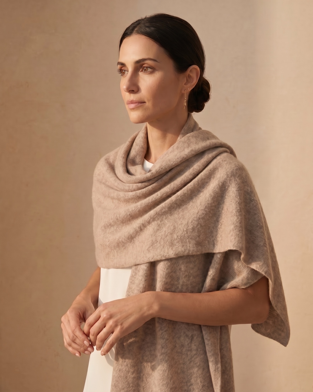 Hugo Caesar Tassi Aquileia cashmere stole in Travertine draped around the shoulders in a warm travertine interior