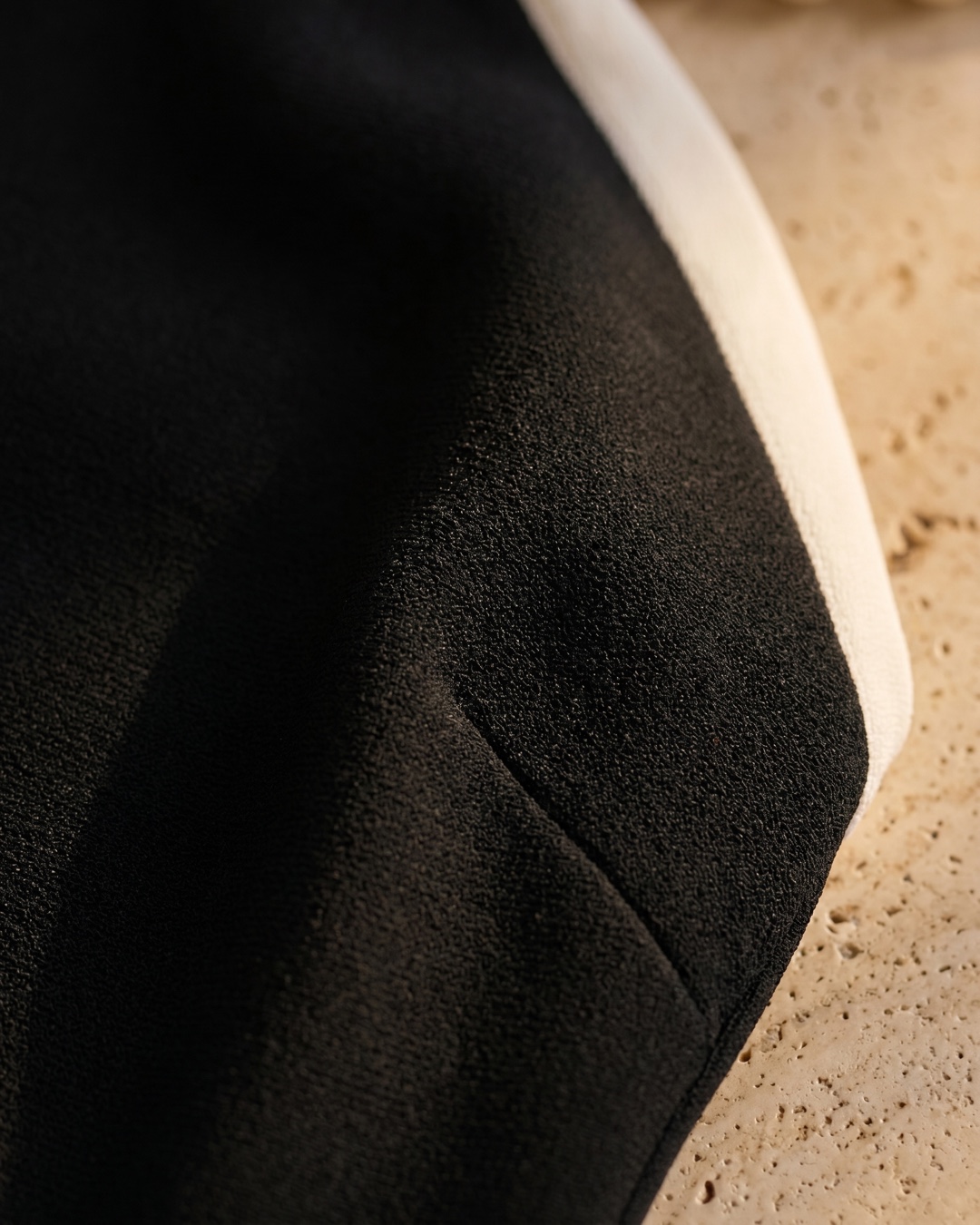 Hugo Caesar Tassi Caecilia fabric macro of dense matte black crepe with the ivory contrast trim edge