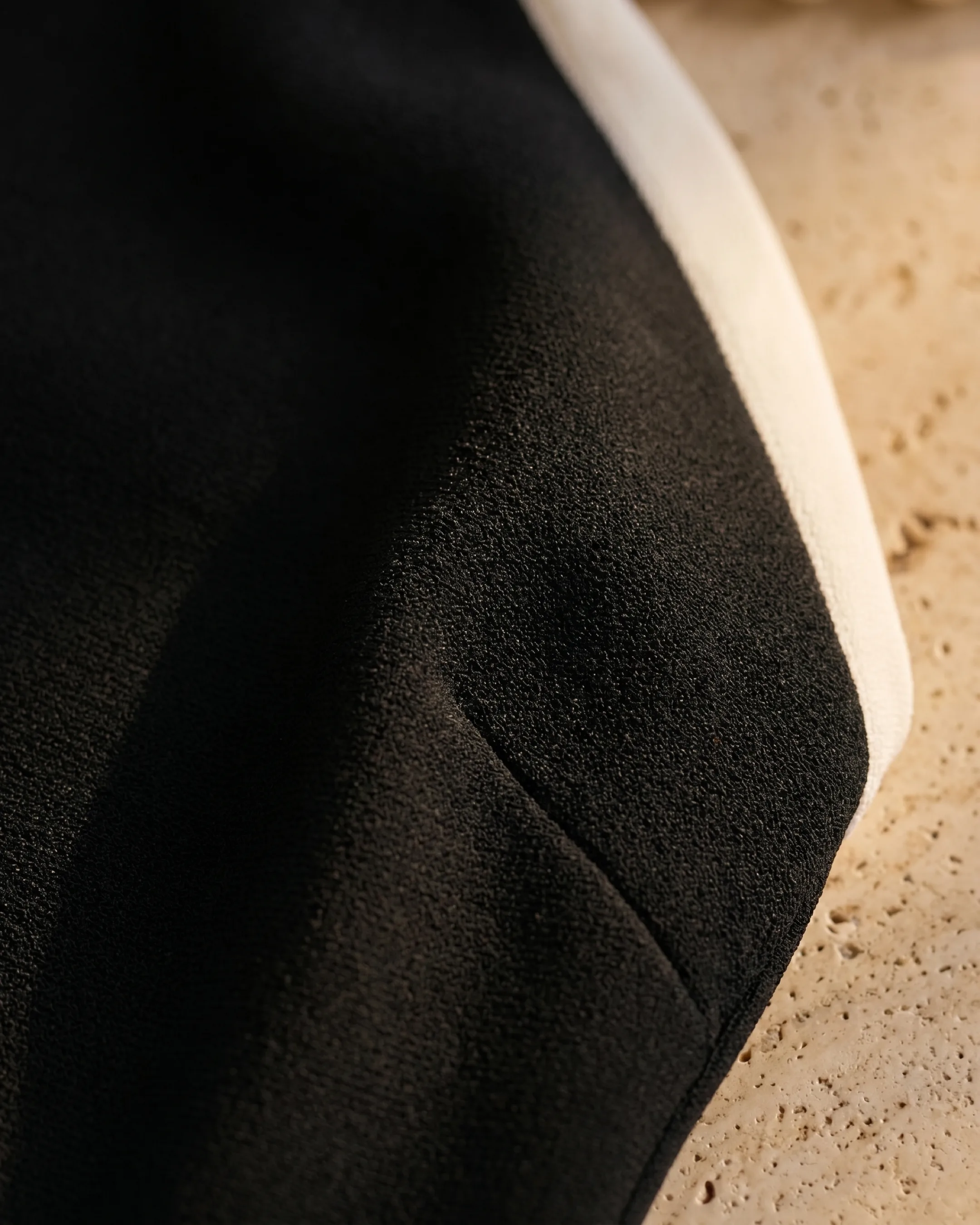 Hugo Caesar Tassi Caecilia fabric macro of dense matte black crepe with the ivory contrast trim edge