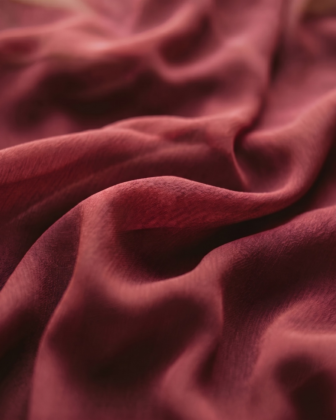 Macro detail of the Hugo Caesar Tassi Claudia gown's fluid Porpora wine-red chiffon and soft ruched folds