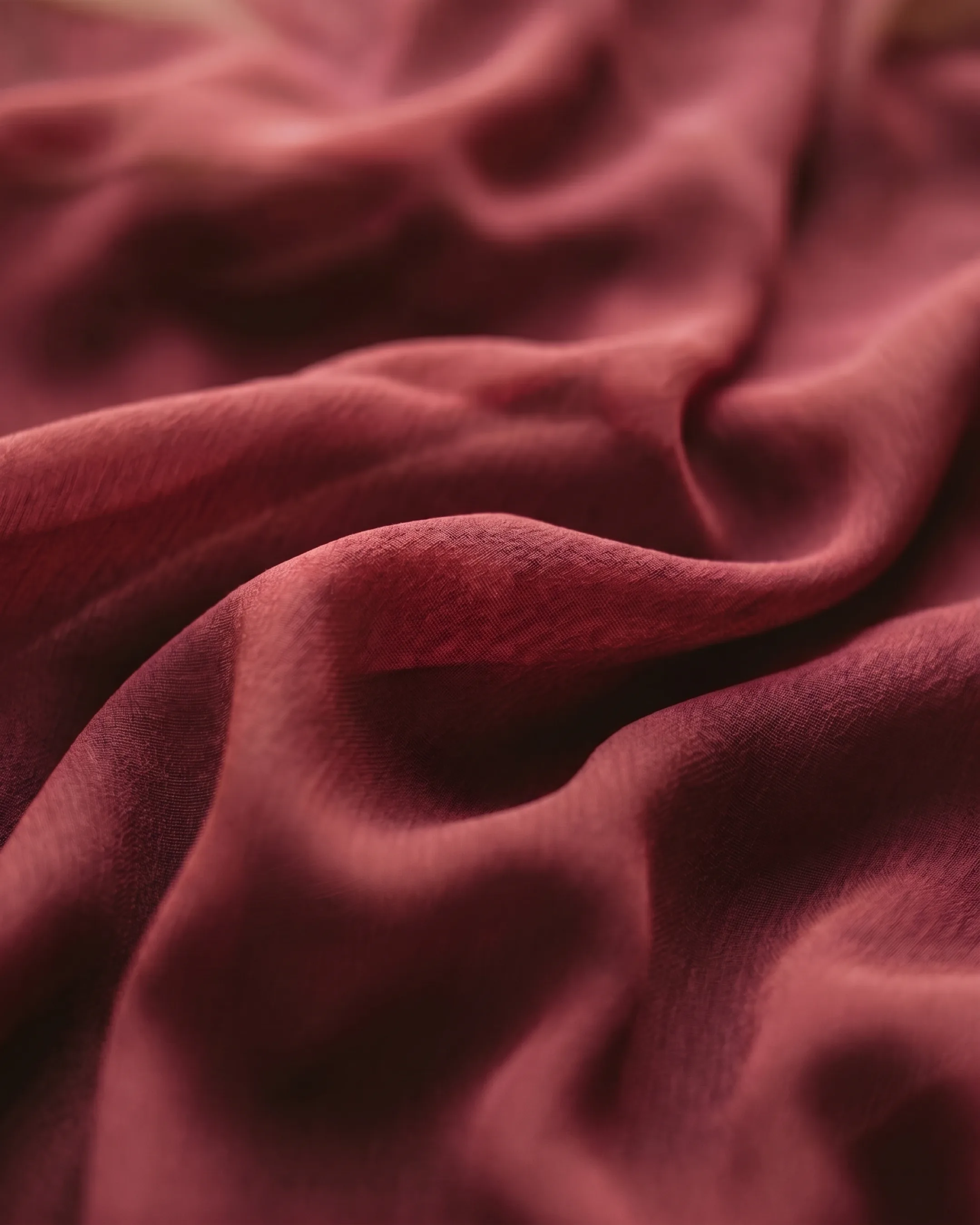 Macro detail of the Hugo Caesar Tassi Claudia gown's fluid Porpora wine-red chiffon and soft ruched folds