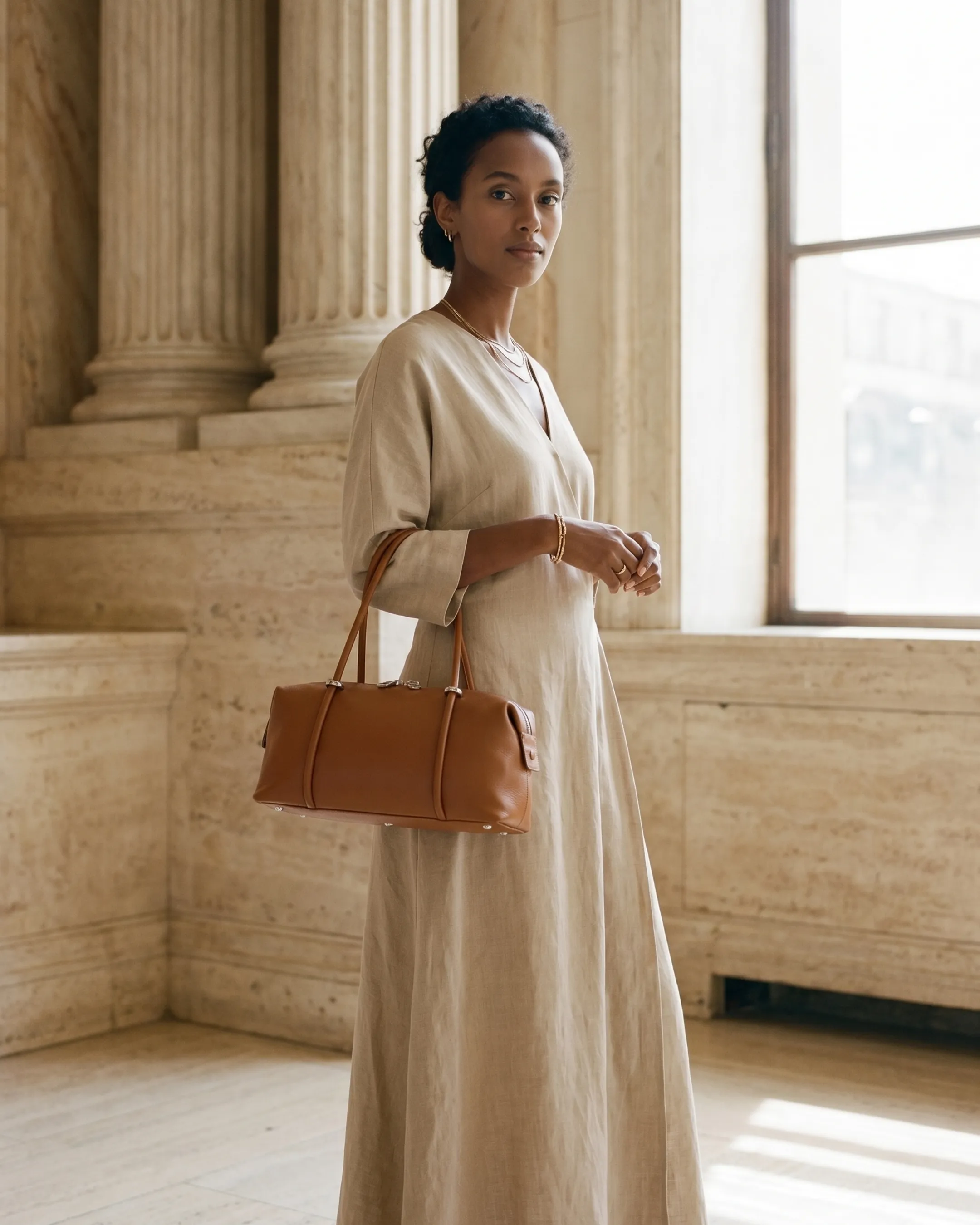 Hugo Caesar Tassi Esquilina leather tote in Travertine tan carried by a model in a columned travertine hall