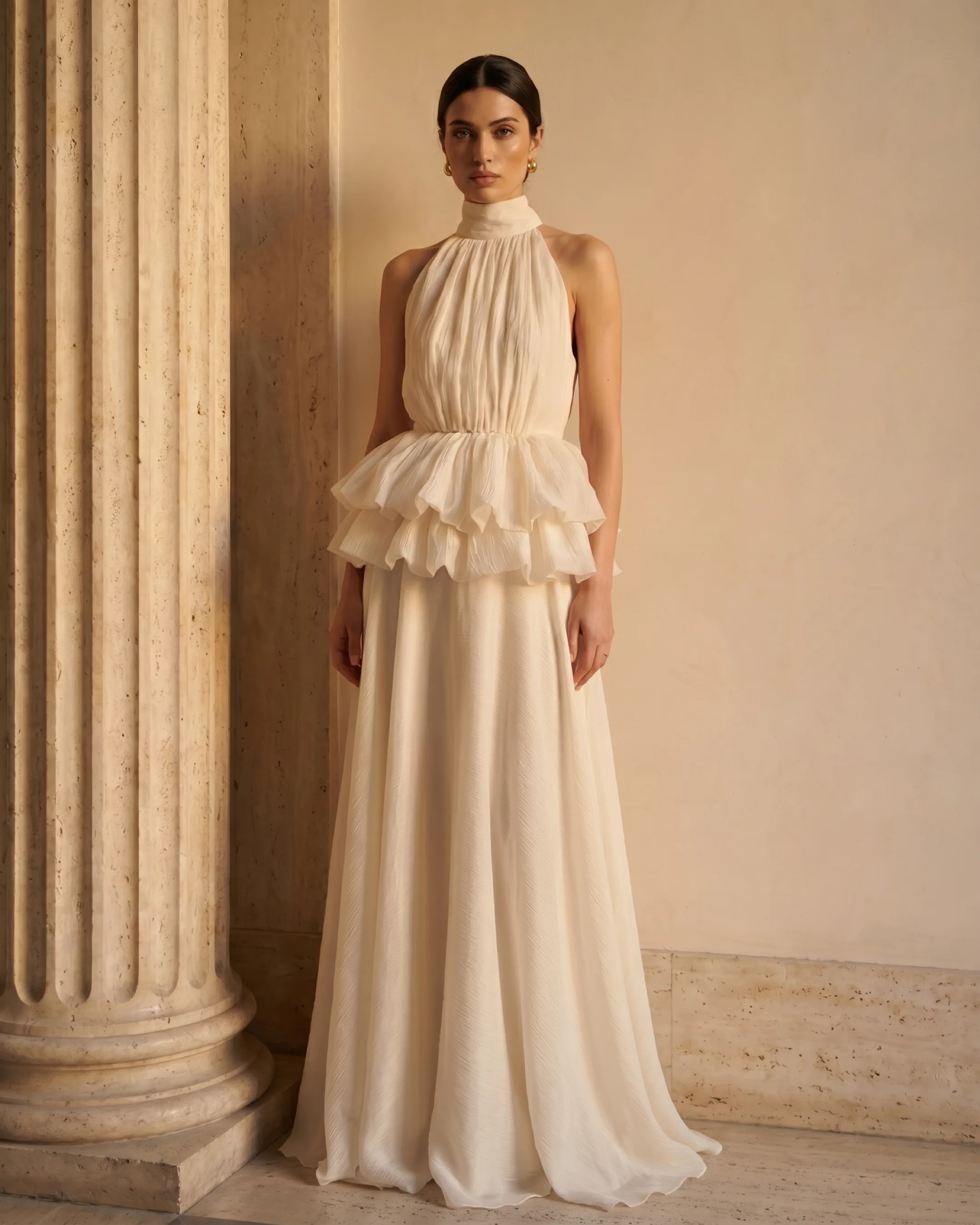 Hugo Caesar Tassi Fulvia stand-collar ruffle crepe dress in Avorio ivory, full-length on the model against a warm travertine wall