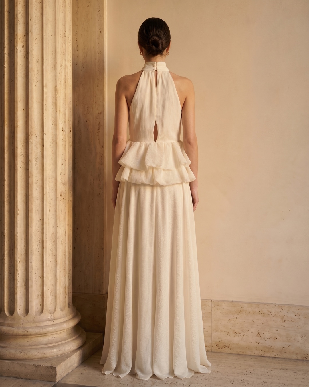 Hugo Caesar Tassi Fulvia full-length rear view showing the buttoned stand collar, soft keyhole back, ruffle peplum and flowing hem