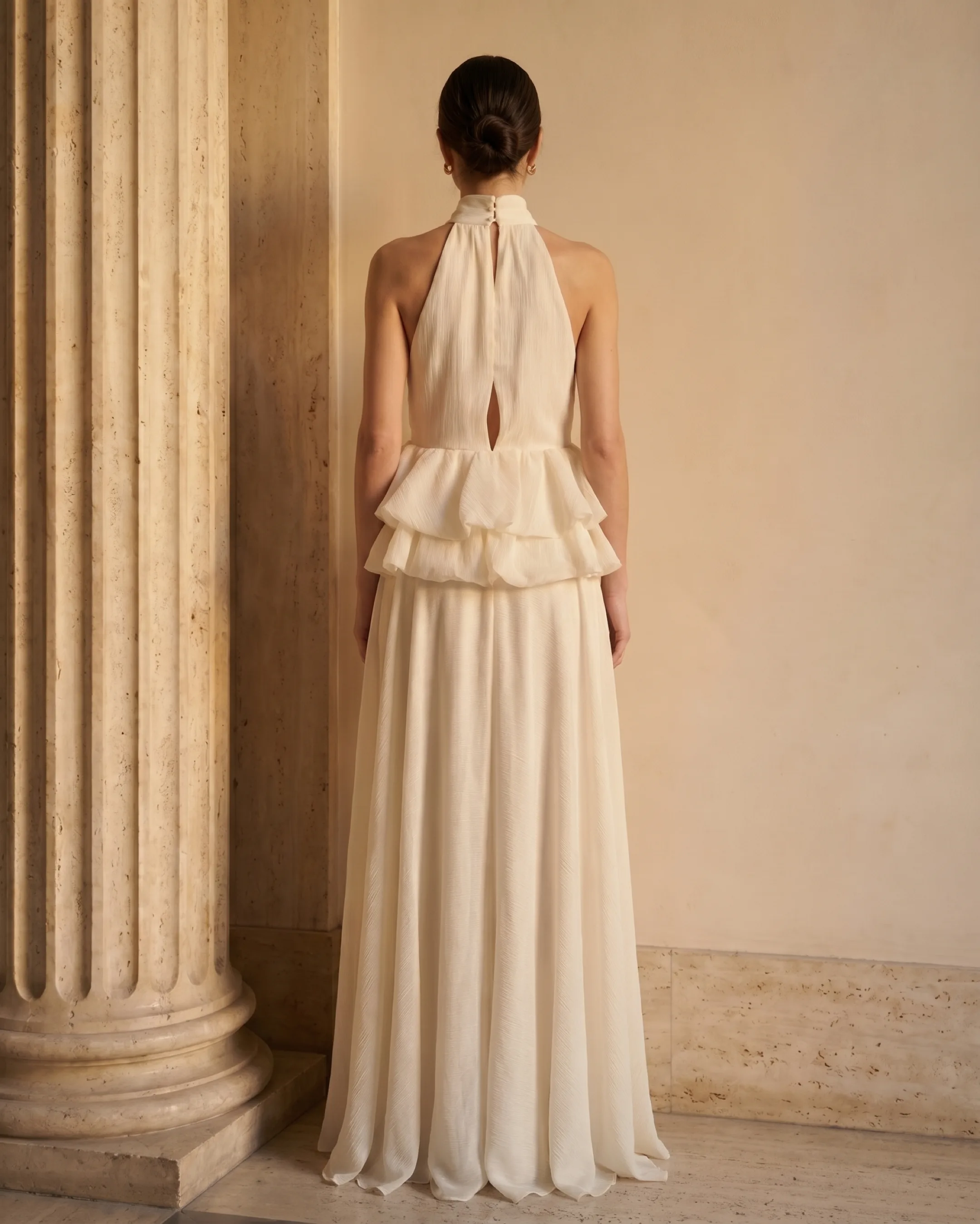 Hugo Caesar Tassi Fulvia full-length rear view showing the buttoned stand collar, soft keyhole back, ruffle peplum and flowing hem