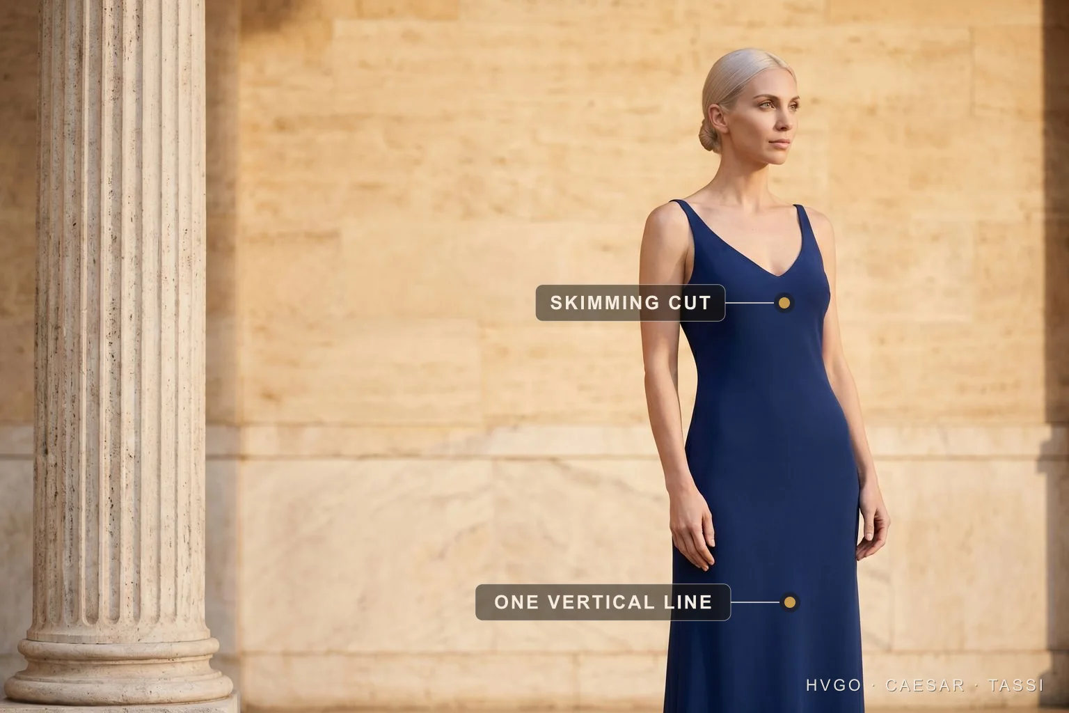 La bella figura — the put-together principle in a navy column gown — Hugo Caesar Tassi Valentina, a platinum-blonde Hugo Caesar Tassi house model, in a deep Cobalto imperial-navy fluid matte-crepe column gown with a soft V-neckline, turned in a relaxed three-quarter contrapposto off-centre beside a fluted Roman travertine column, labelled to show the skimming cut at the bodice and the one unbroken vertical line falling from waist to hem in a sunlit travertine setting
