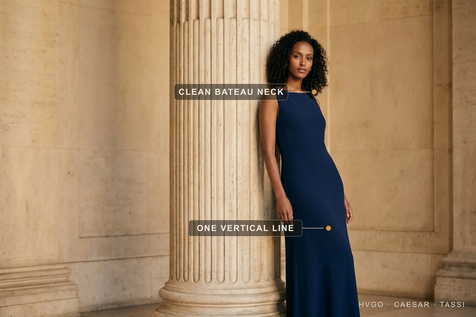 How to choose a dress — match the occasion with one unbroken column line — Hugo Caesar Tassi Aisha, a Hugo Caesar Tassi house model with dark natural curls, in a Cobalto deep-navy matte-crepe column gown leaning in contrapposto against a fluted Roman travertine column, labelled to show the clean bateau neckline and the single unbroken vertical line of the skirt, in a warm Roman travertine colonnade