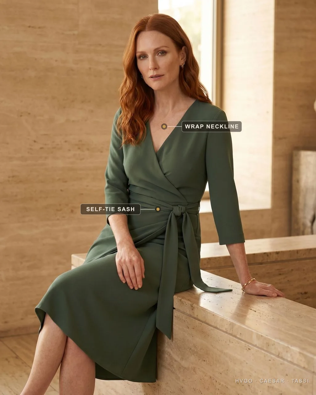 Auburn-haired model Elena seated on a travertine ledge in a forest-green Aurelia Self-Tie Wrap Crepe Midi dress, labels marking the surplice wrap neckline and the knotted self-tie sash at the waist.