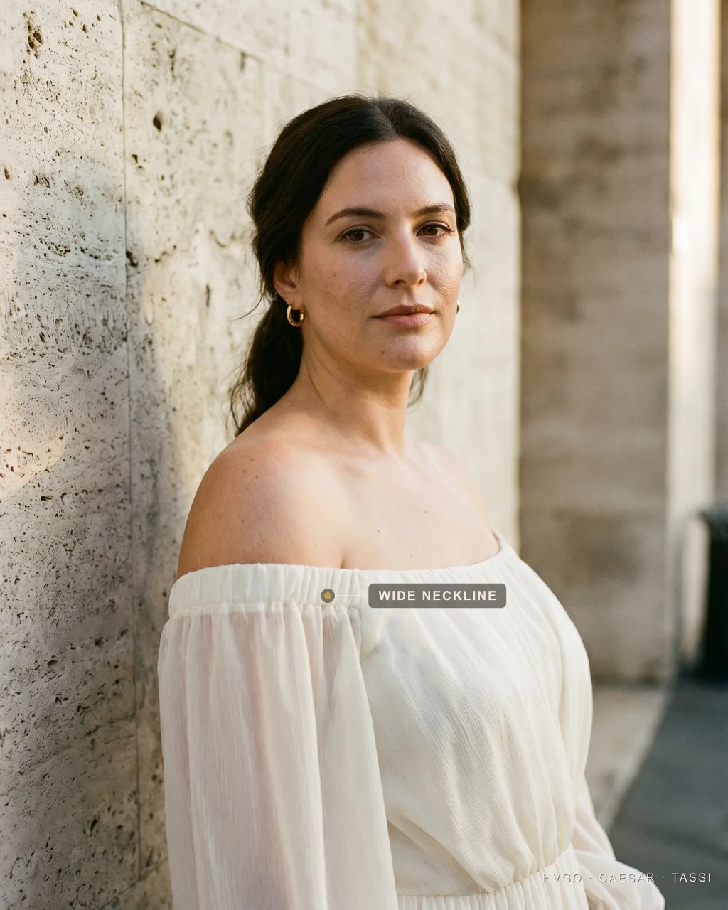 Wide boat neckline for a pear body shape — Hugo Caesar Tassi Close view of a woman with a pear body shape in a Hugo Caesar Tassi ivory chiffon gown with a wide boat neckline, labelled to show the wide neckline broadening the shoulder and lifting the eye