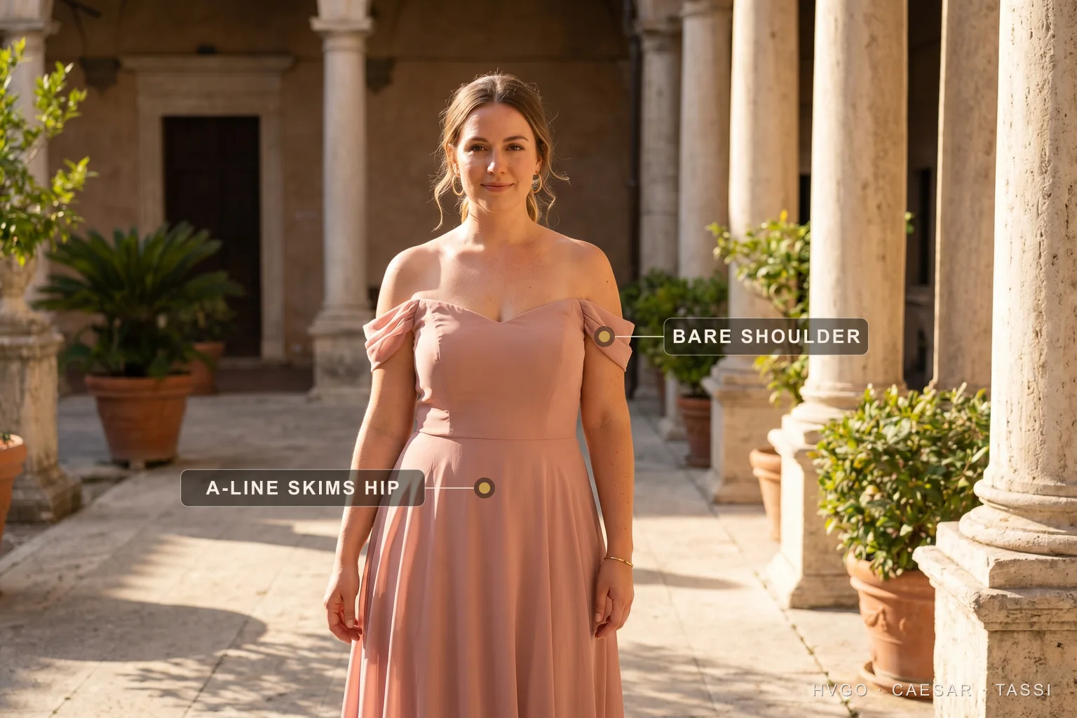 Off-shoulder A-line gown for a pear body shape — Hugo Caesar Tassi A woman with a pear body shape in a Hugo Caesar Tassi off-shoulder A-line chiffon gown in a Roman courtyard, labelled to show the off-shoulder line broadening the shoulder and the A-line skirt skimming the hip