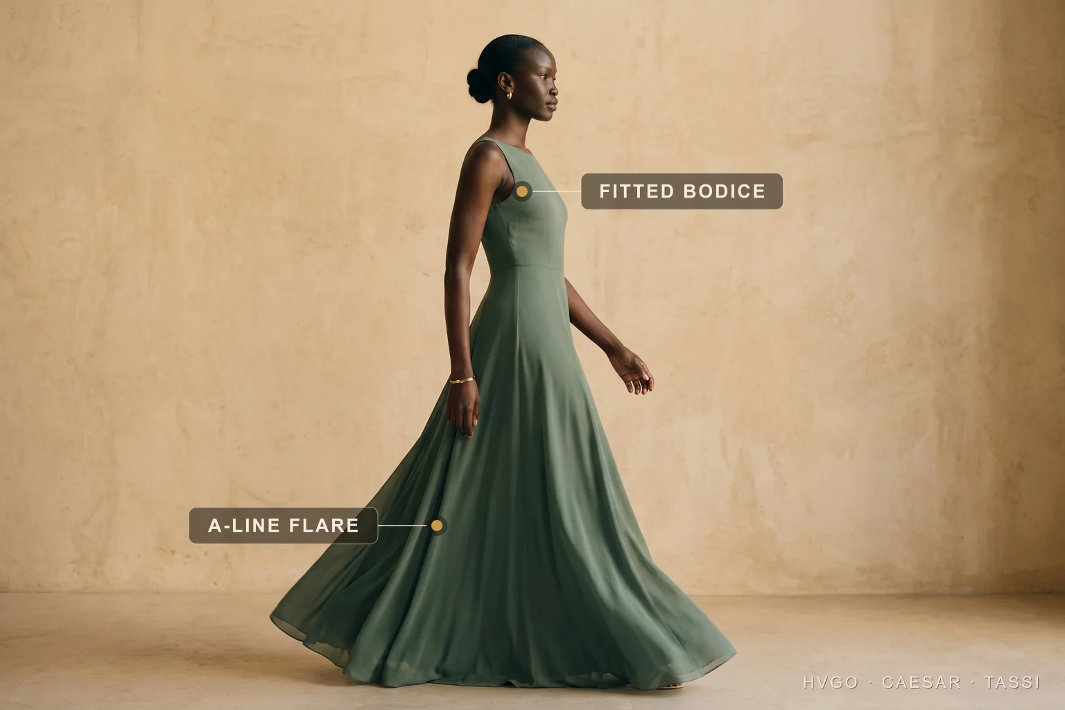 Dress silhouettes explained — the A-line widening triangle — Hugo Caesar Tassi A woman in a Hugo Caesar Tassi Verde-Antico sage-green chiffon A-line gown caught mid-stride in a Roman travertine studio, the skirt swinging out, labelled to show the fitted bodice and the A-line skirt flaring into a widening triangle