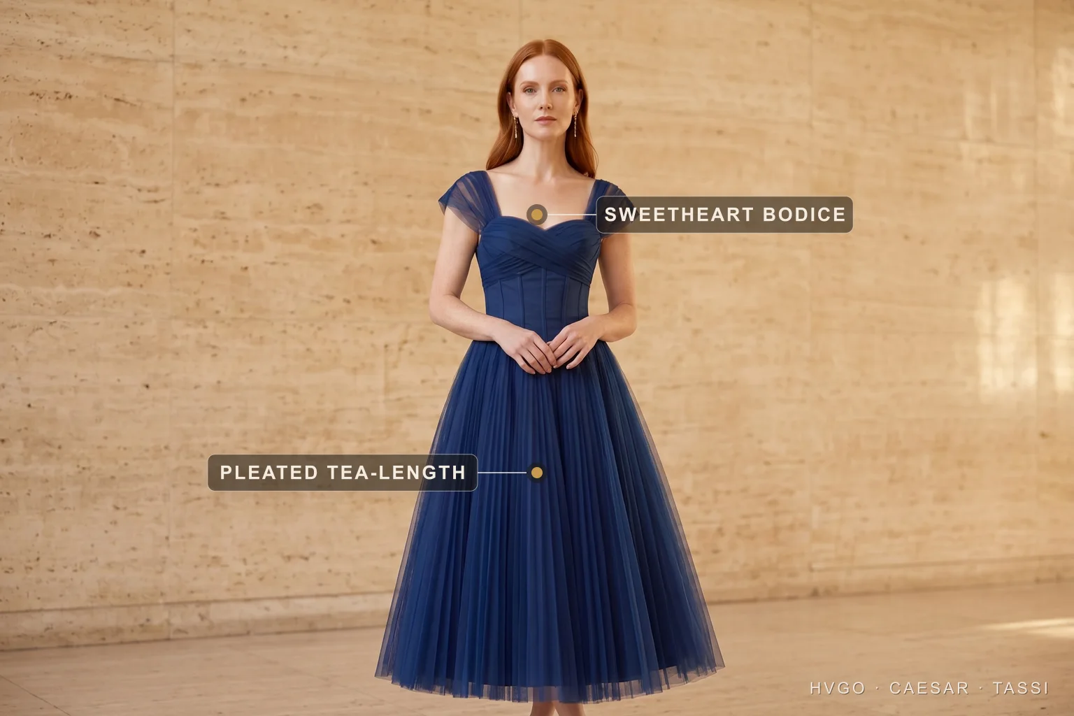 Formal wedding guest pleated tea-length dress — Hugo Caesar Tassi A wedding guest in a Hugo Caesar Tassi cobalt-navy pleated tea-length dress with a sweetheart bodice, labelled to show the sweetheart bodice and the pleated tea-length skirt — the formal answer with room for colour