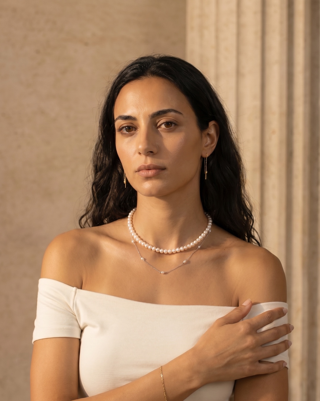 Hugo Caesar Tassi Laurea double-layer pearl and silver necklace worn at the throat and décolletage against a warm travertine wall