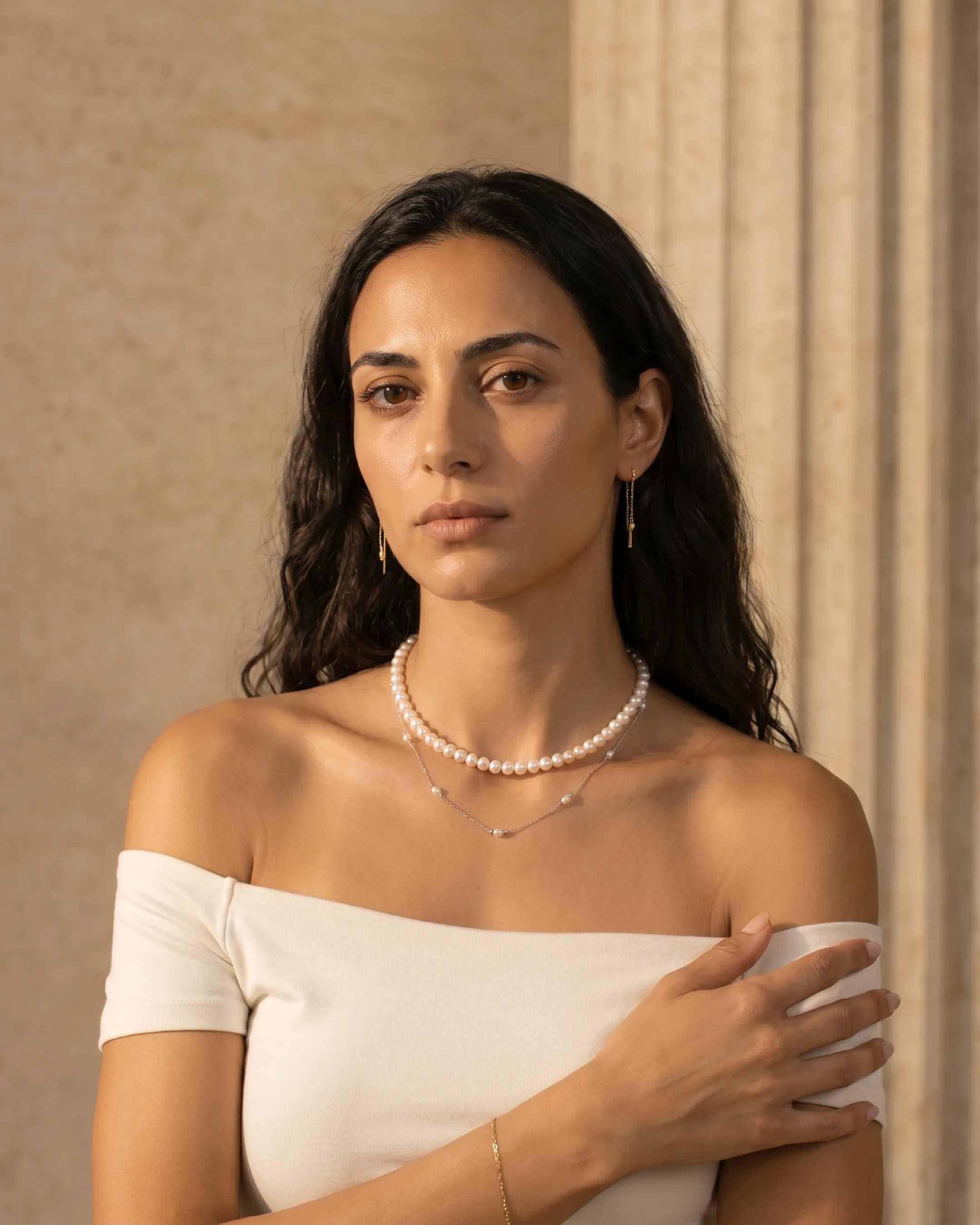 Hugo Caesar Tassi Laurea double-layer pearl and silver necklace worn at the throat and décolletage against a warm travertine wall