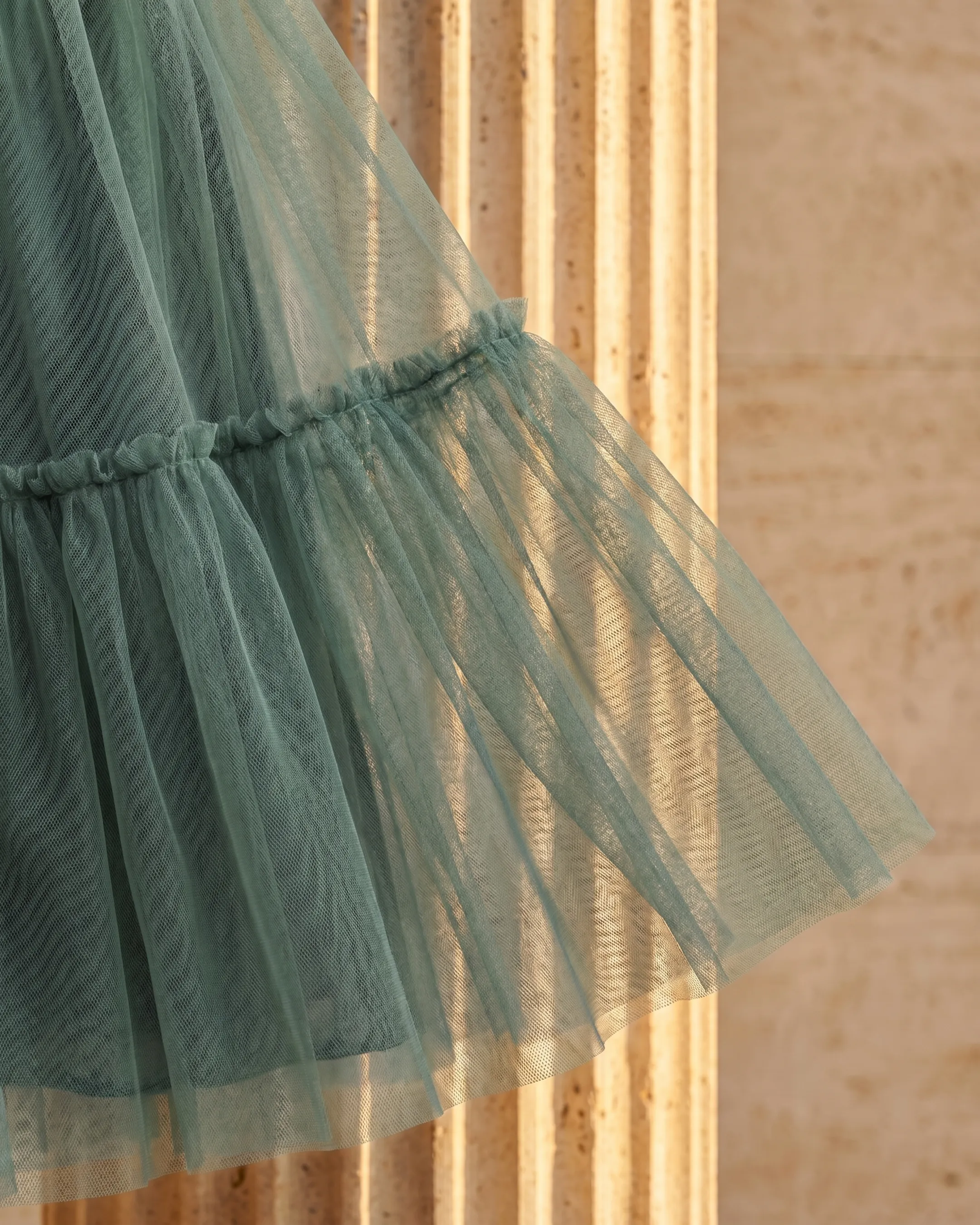 Macro detail of the Hugo Caesar Tassi Marcia dress's sheer layered sage green Verde Antico tulle and gathered ruffle frill