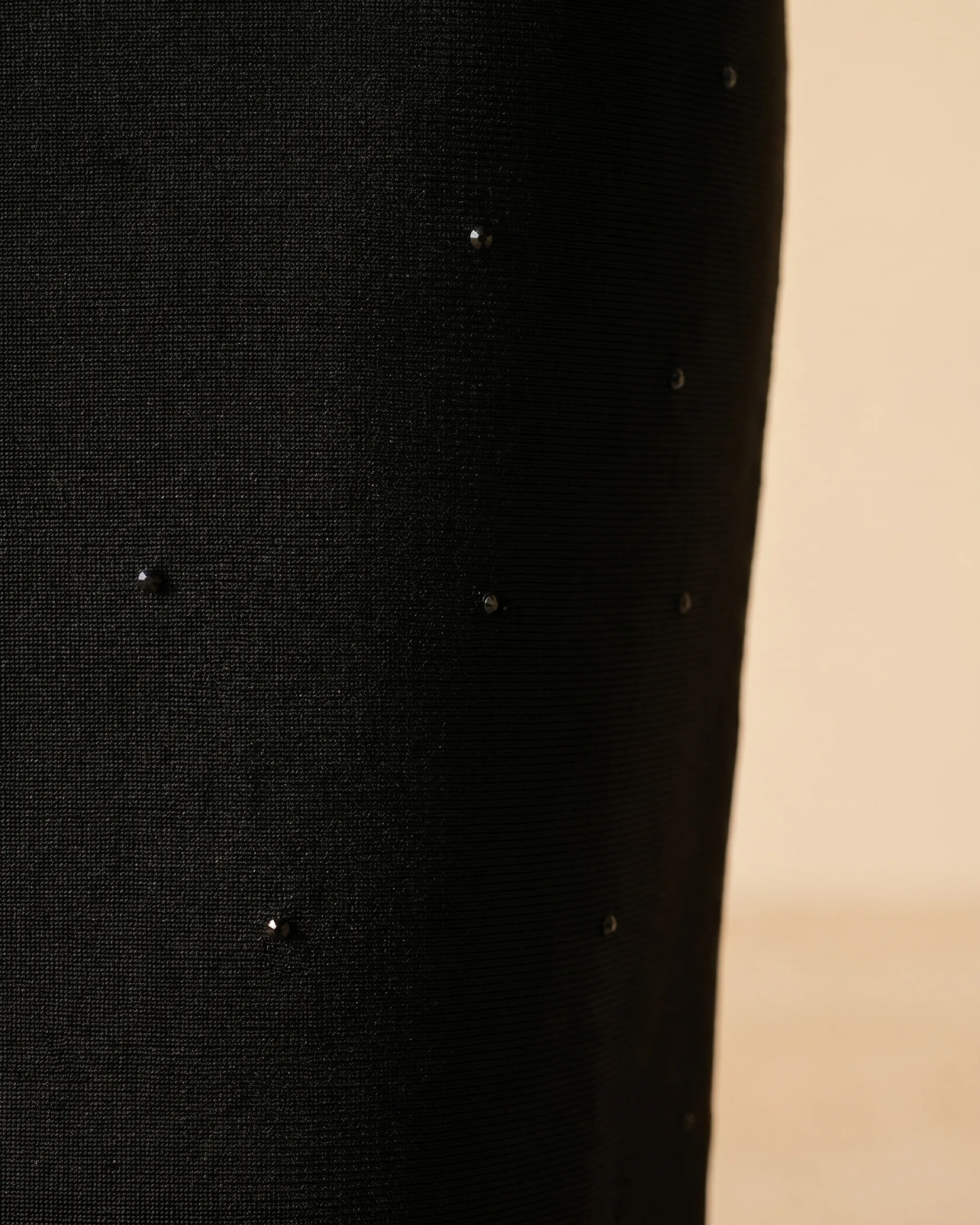 Hugo Caesar Tassi Mucia macro of the dense black bandage knit with a sparse tonal crystal detail catching soft light
