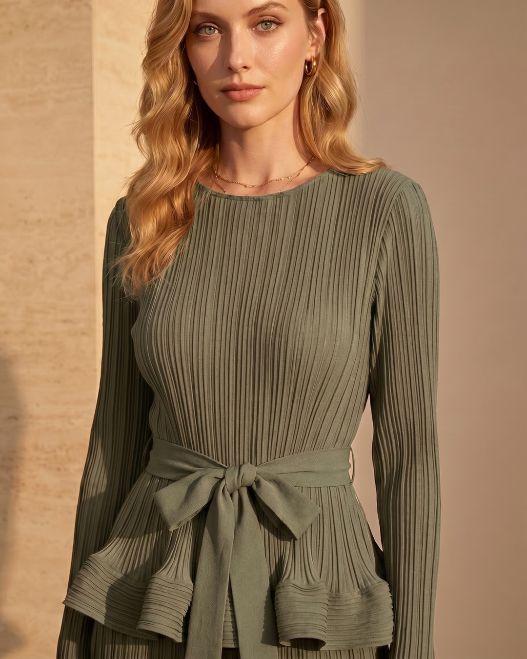 Hugo Caesar Tassi Munatia close-up of the round neckline, fine vertical pleating and self-tie bow belt at the high waist in sage-green pleated crepe