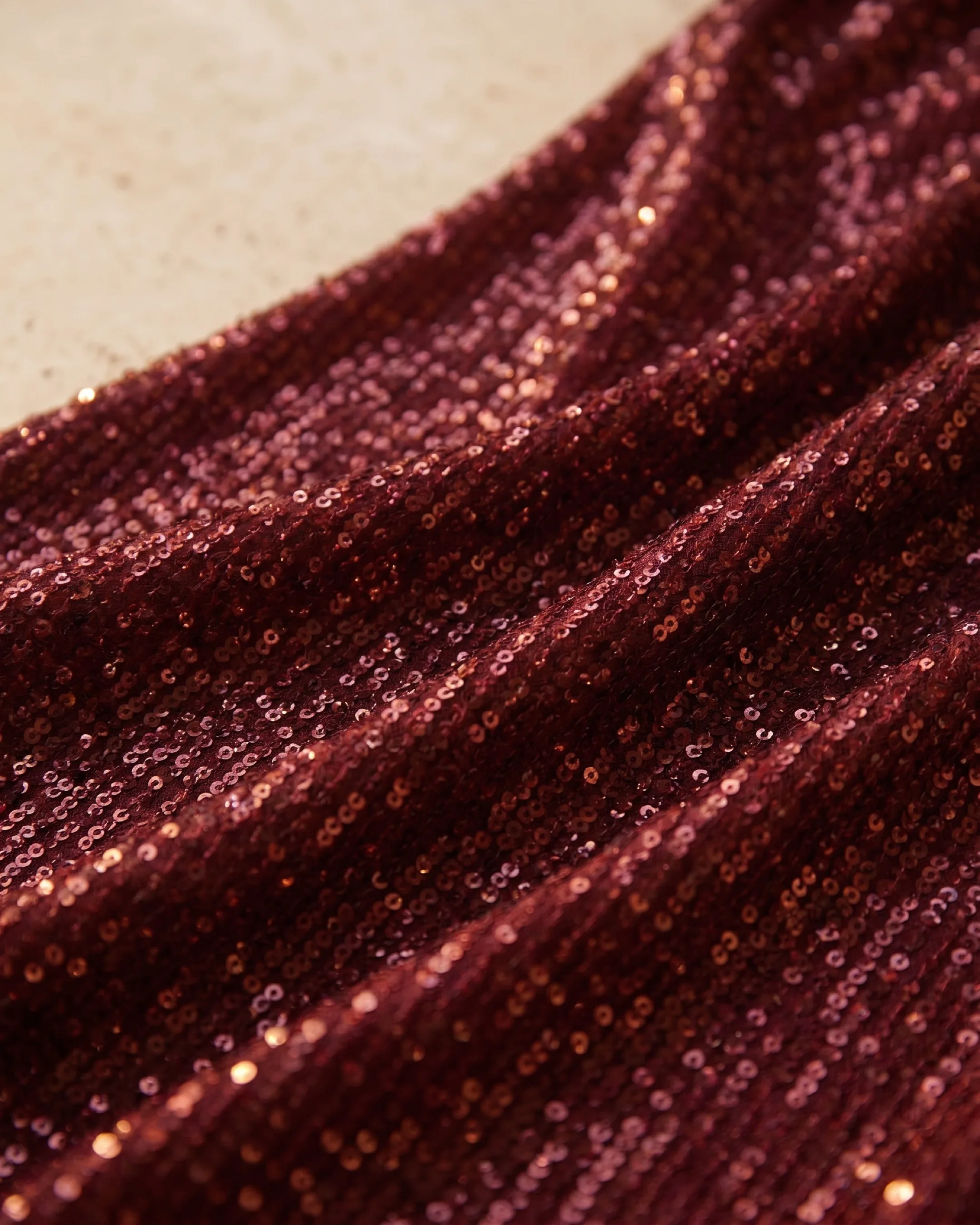 Hugo Caesar Tassi Norbana macro of the fine all-over sequins on stretch crepe in deep Porpora wine, a soft restrained shimmer in golden light