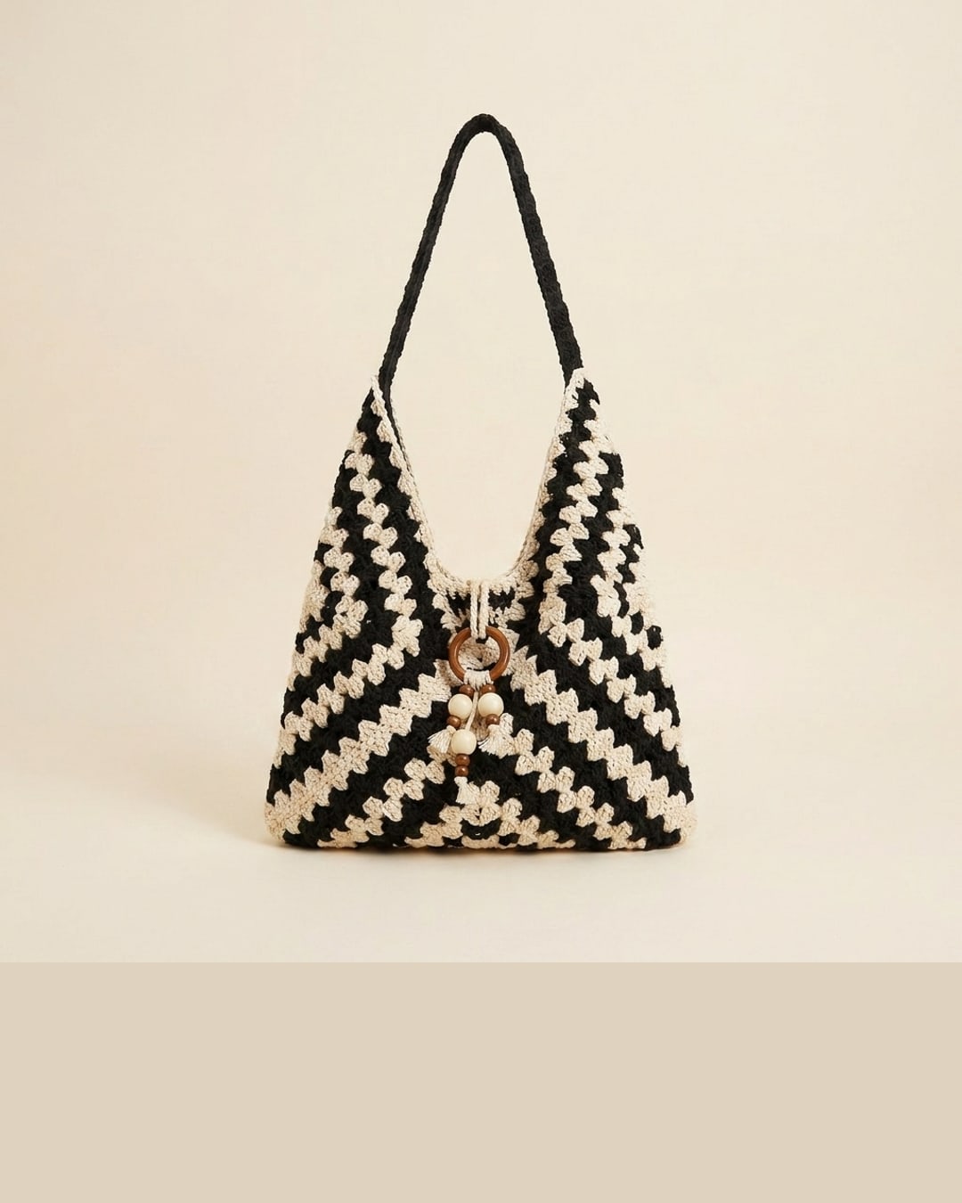 The Ostia tote in Basalt — a clean studio packshot of the near-black and cream hand-crocheted chevron weave