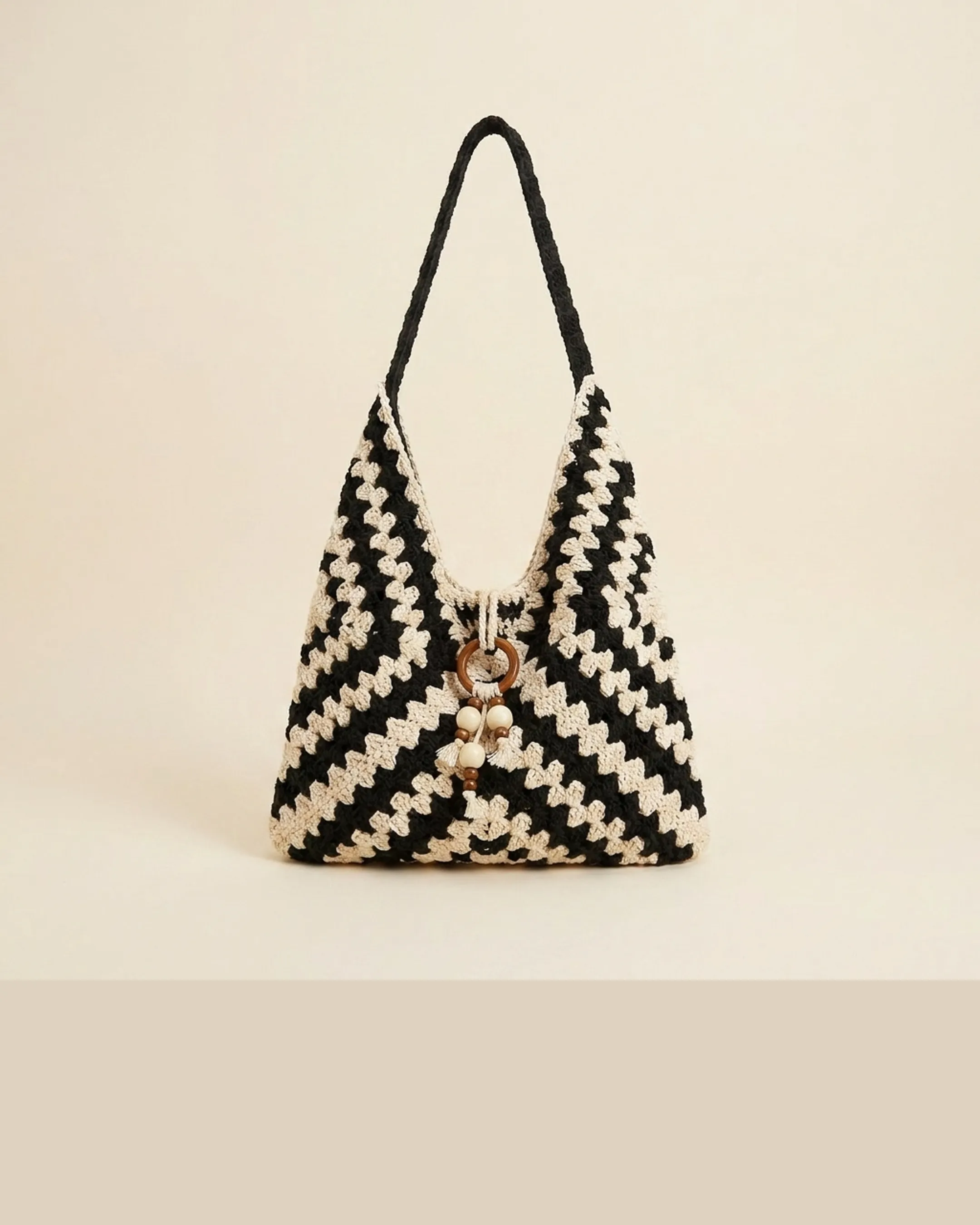 The Ostia tote in Basalt — a clean studio packshot of the near-black and cream hand-crocheted chevron weave