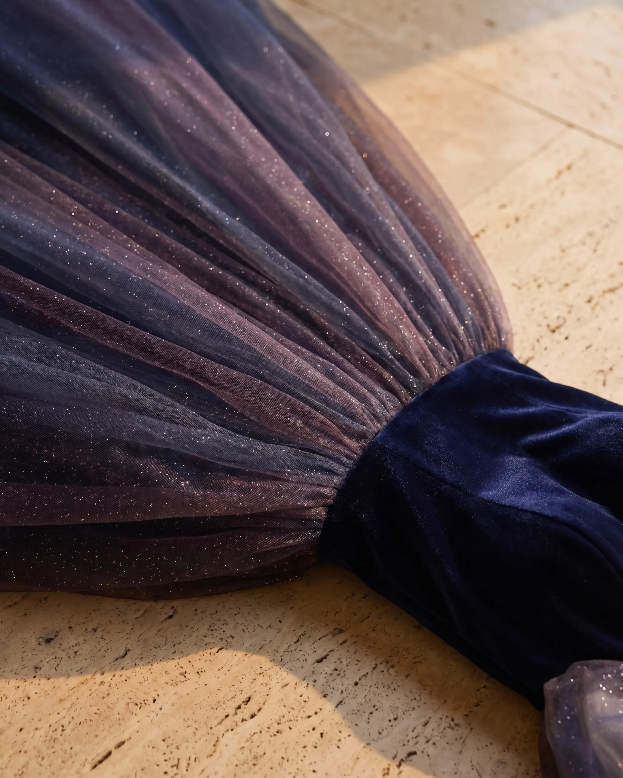 Hugo Caesar Tassi Petronia fabric macro of deep navy velvet beside galaxy-ombre glittered tulle catching golden light