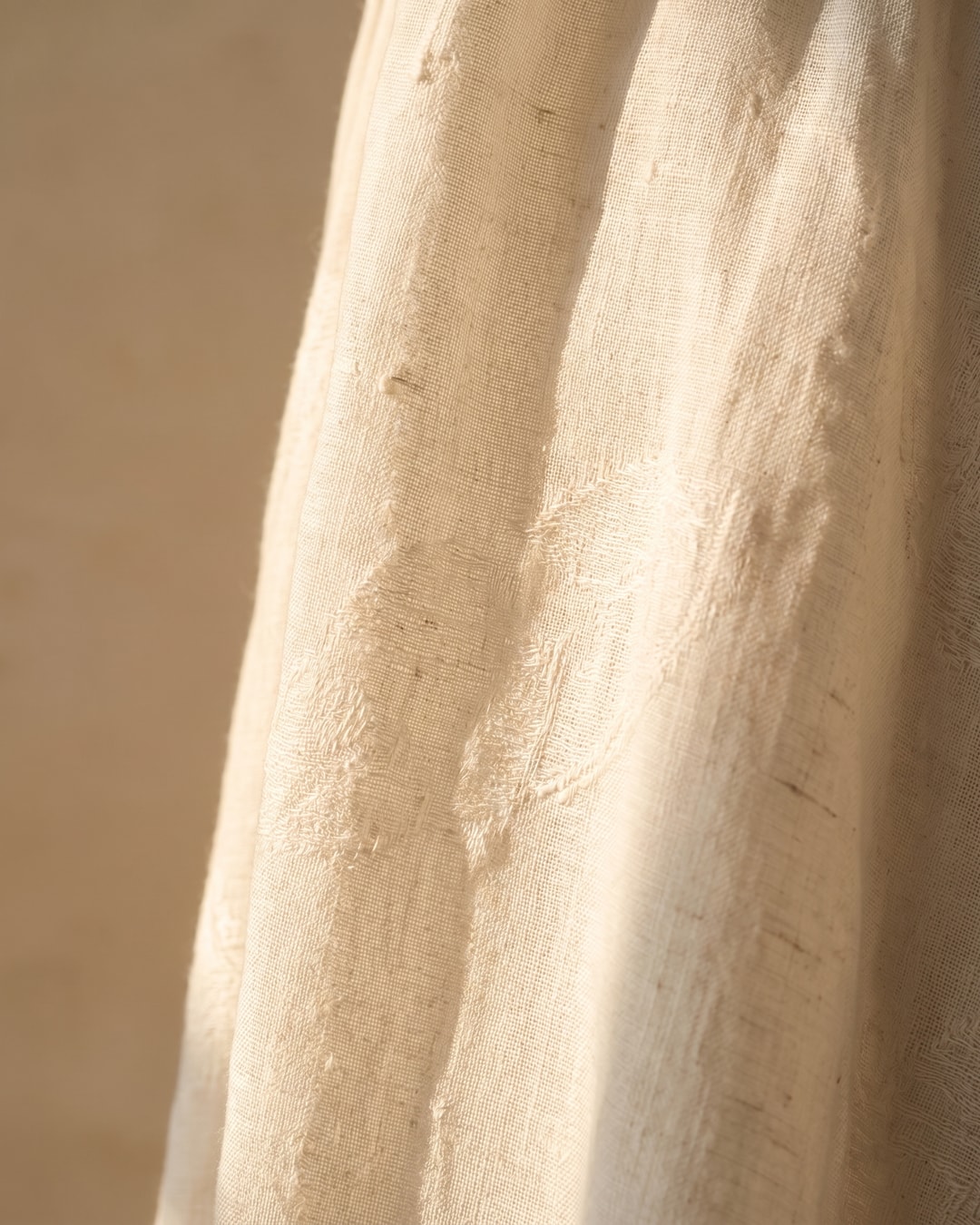 Macro detail of the Hugo Caesar Tassi Pomponia dress's natural Avorio ivory linen weave with its faint tone-on-tone woven floral