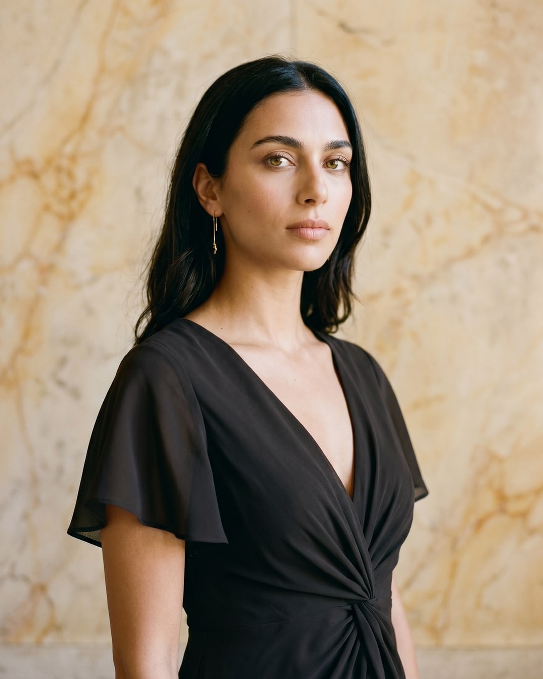 Portia chiffon dress in Basalt — three-quarter bodice detail of the deep V-neck, flutter sleeve and signature twist-knot waist, Hugo Caesar Tassi, warm travertine studio