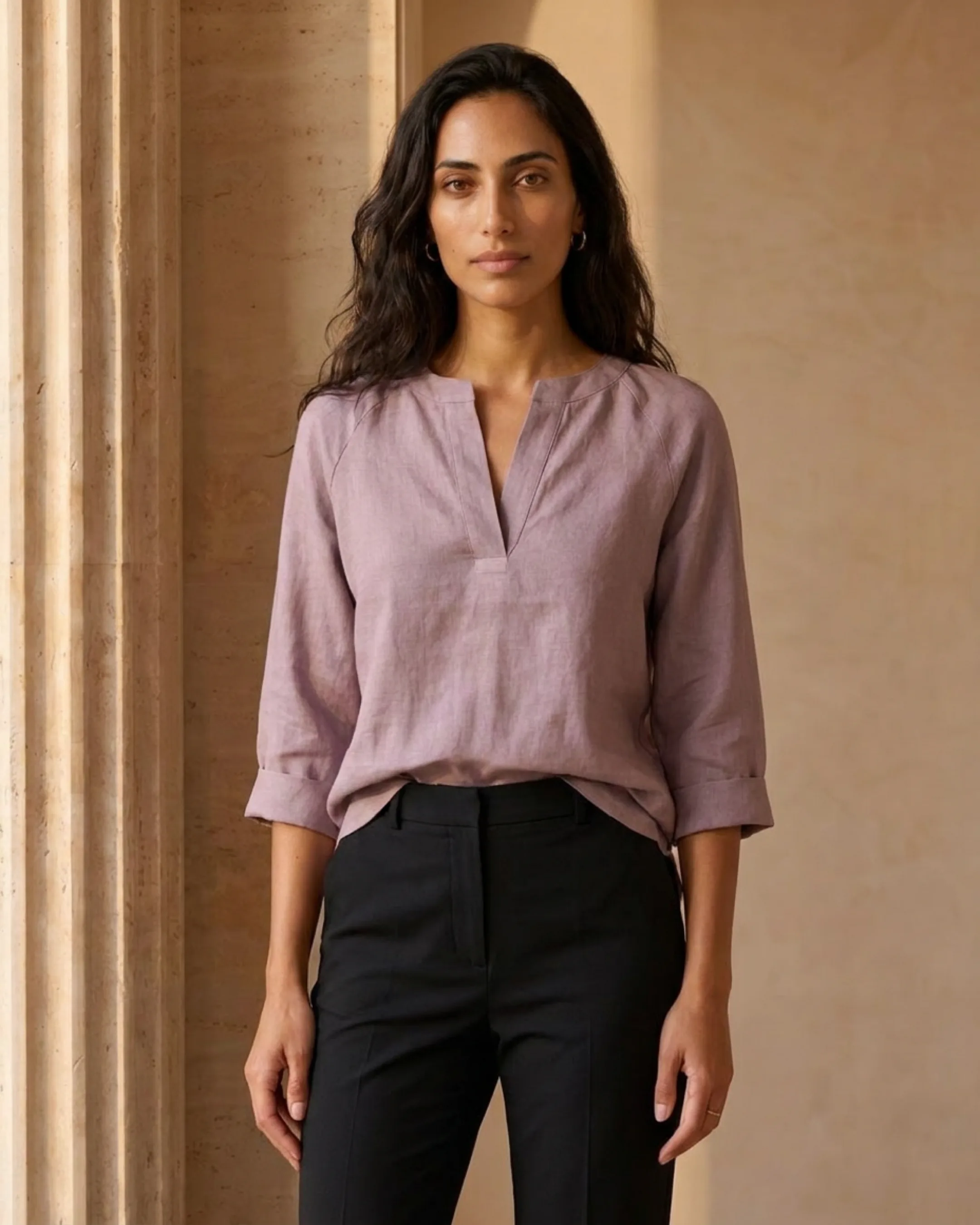 Hugo Caesar Tassi Roscia structured long-sleeve ramie blouse in smoky Lavanda, front view tucked into tailored trousers by a travertine wall