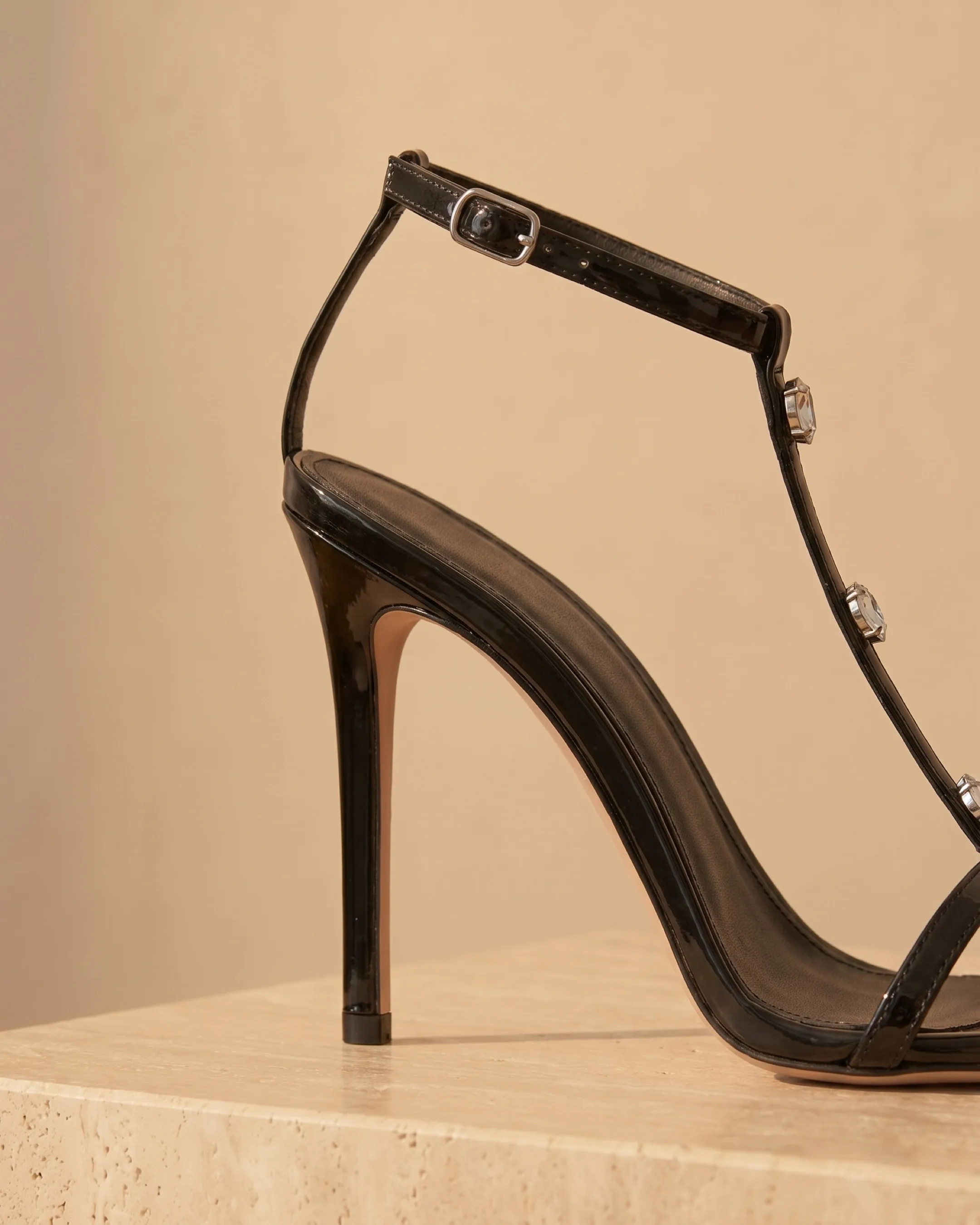 Hugo Caesar Tassi Sabella macro of the slim black patent stiletto heel, the fine T-bar and the clear crystal accents in claw settings