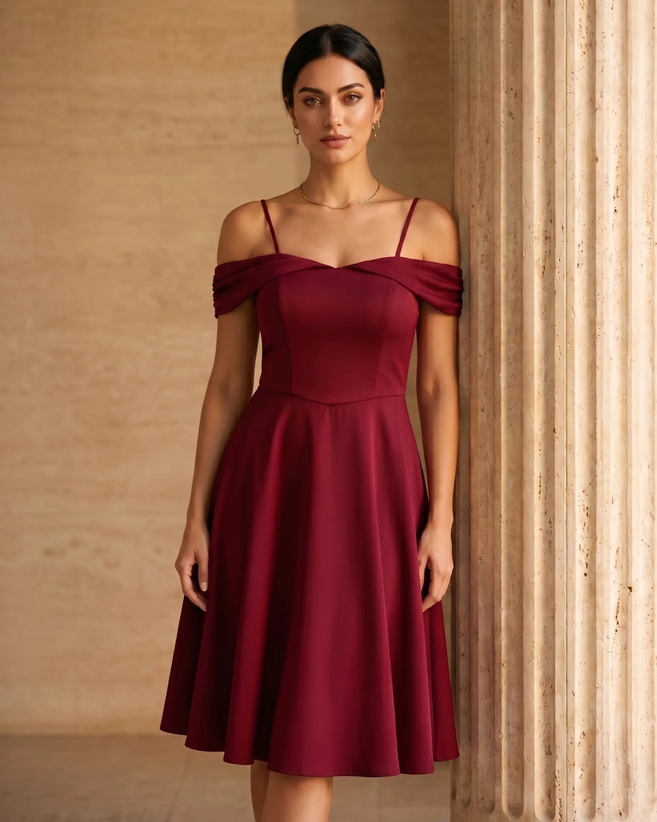 Hugo Caesar Tassi Sabina off-shoulder fit-and-flare cocktail dress in Porpora wine, full-length on the model against a warm travertine wall