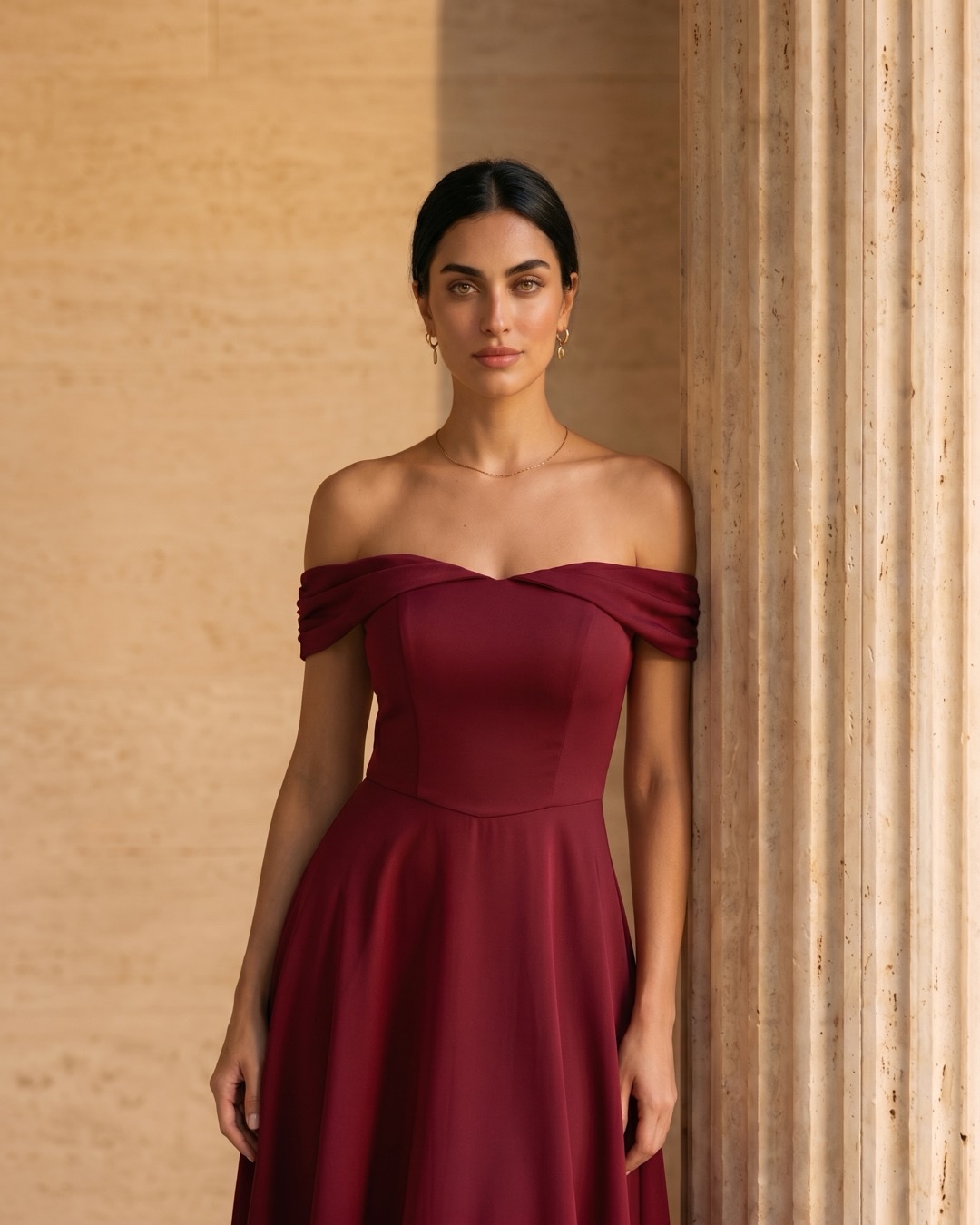 Hugo Caesar Tassi Sabina off-shoulder cocktail dress photographed beside a fluted travertine column in soft golden afternoon light