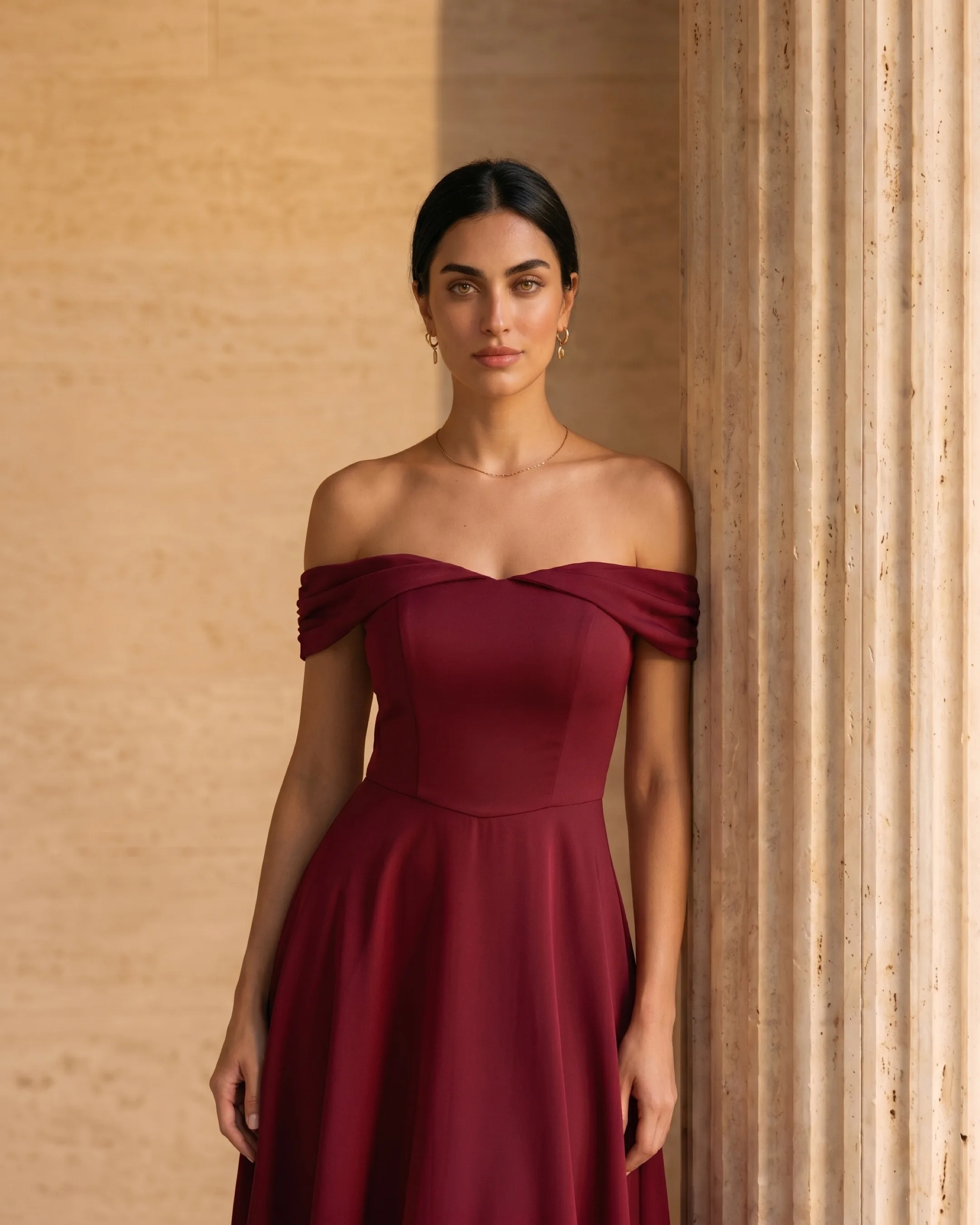 Hugo Caesar Tassi Sabina off-shoulder cocktail dress photographed beside a fluted travertine column in soft golden afternoon light