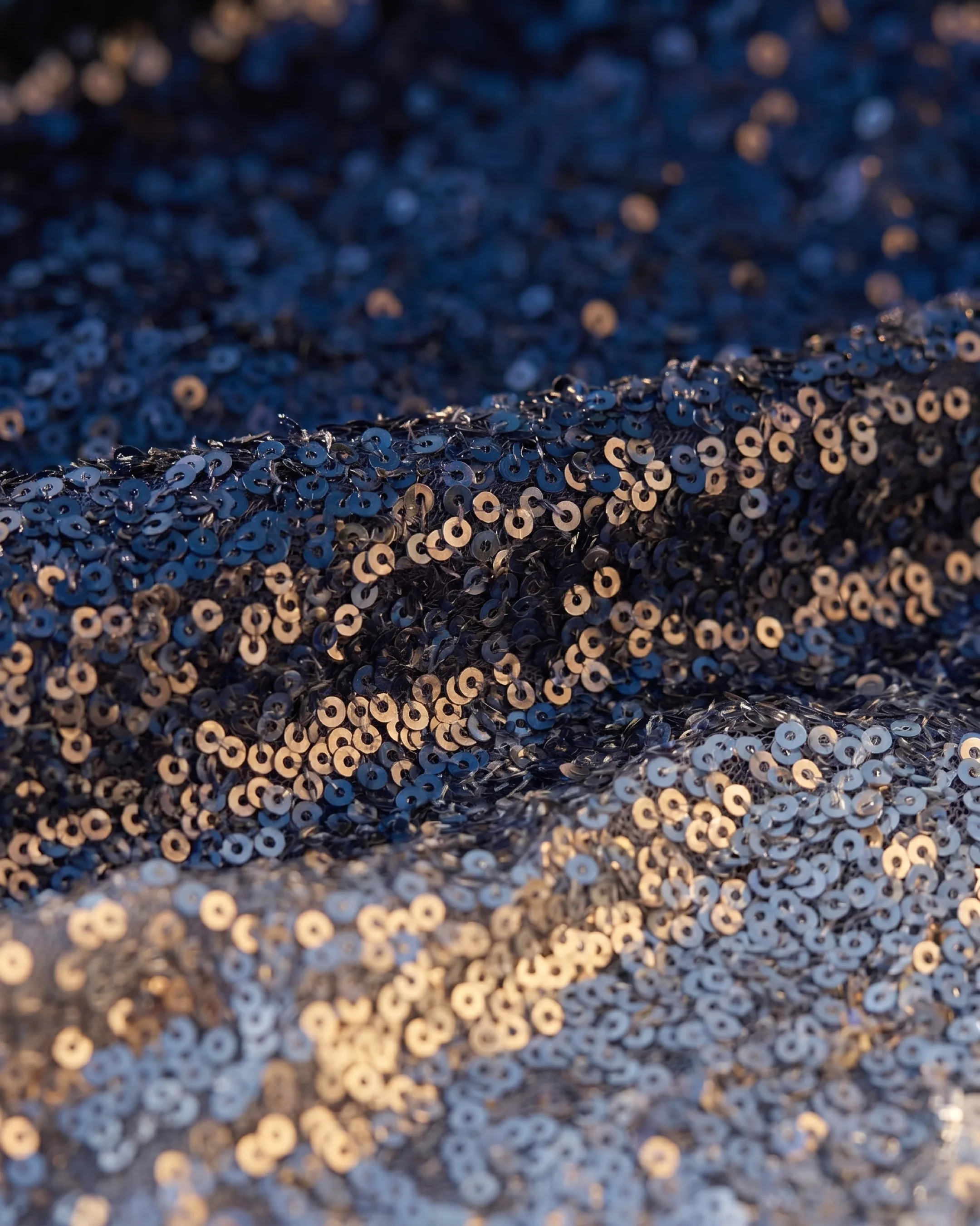 Hugo Caesar Tassi Sempronia fabric macro of fine navy-to-silver ombre sequins catching golden light
