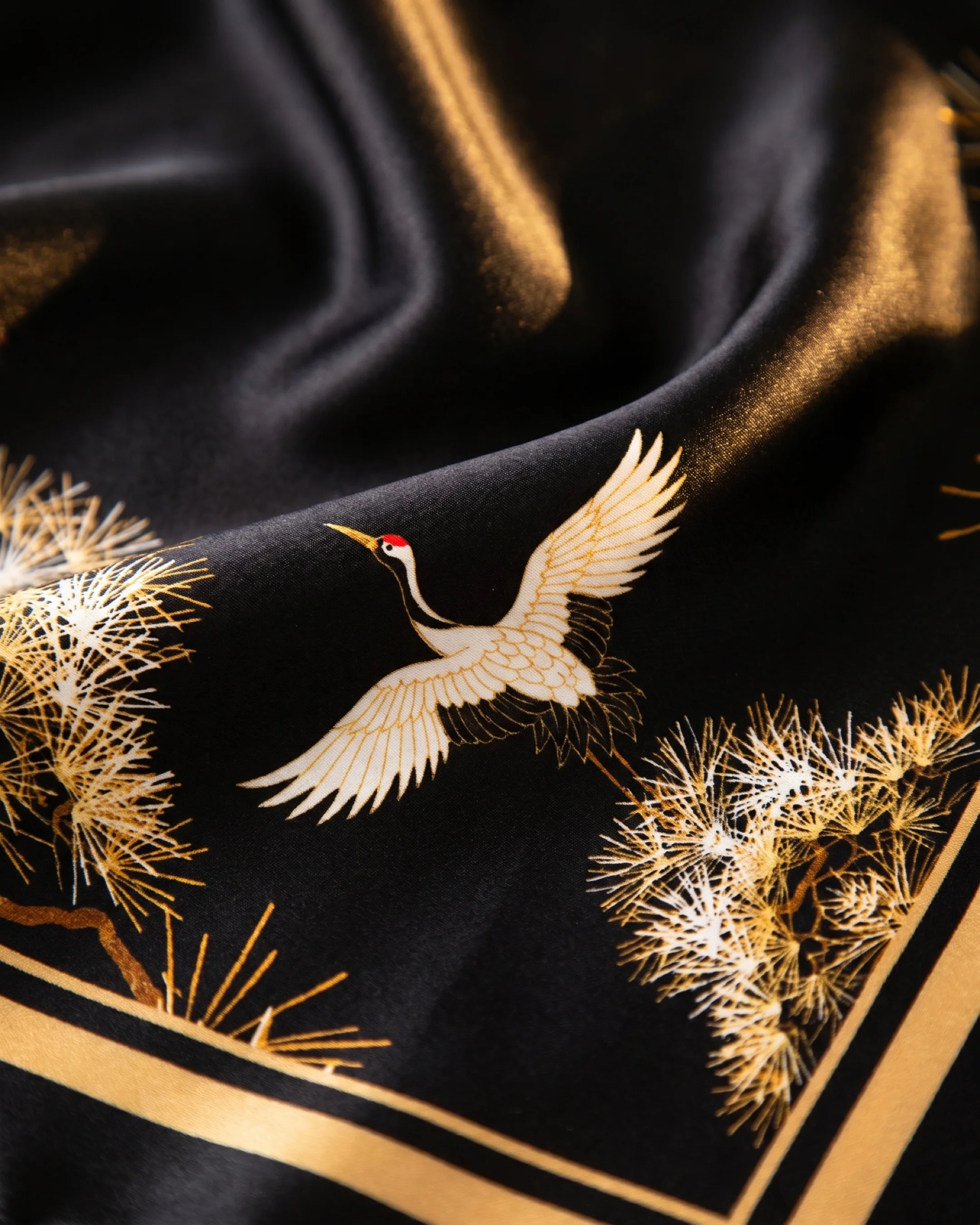 Hugo Caesar Tassi Spoleto macro of the glossy black silk satin showing a white flying crane, golden pine sprays and the gold border line