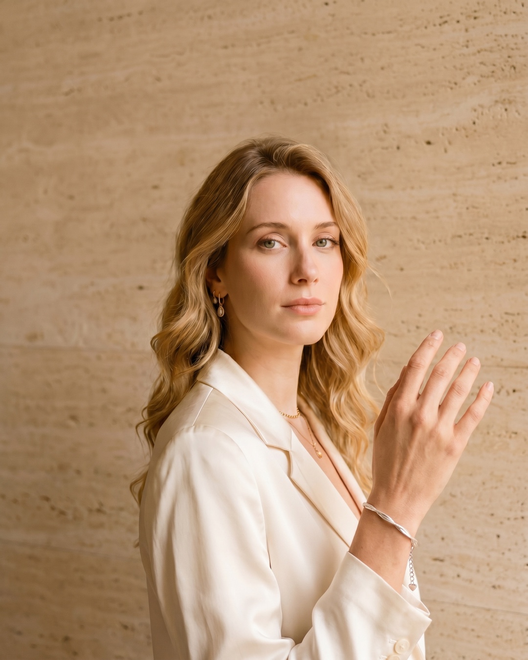 Hugo Caesar Tassi Stella twisted multi-strand silver bracelet draped around the wrist against a warm travertine wall