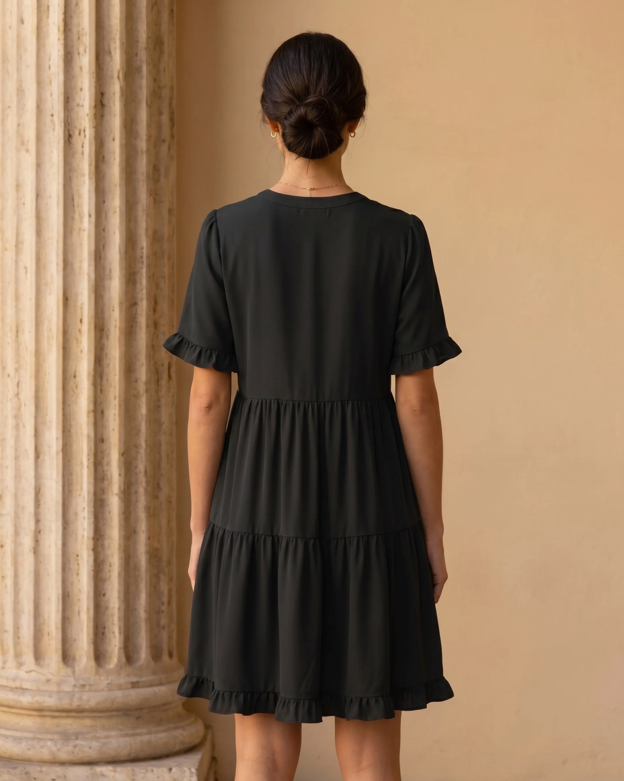 Hugo Caesar Tassi Tertulla full-length rear view showing the plain round back neckline, flutter sleeves and gathered tiered swing skirt