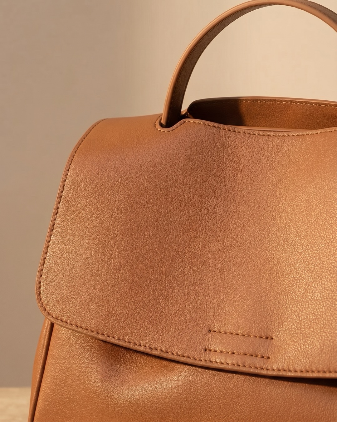 Hugo Caesar Tassi Tiberina macro of the pebbled cognac leather grain, the arched top handle and the curved flap edge with neat stitching