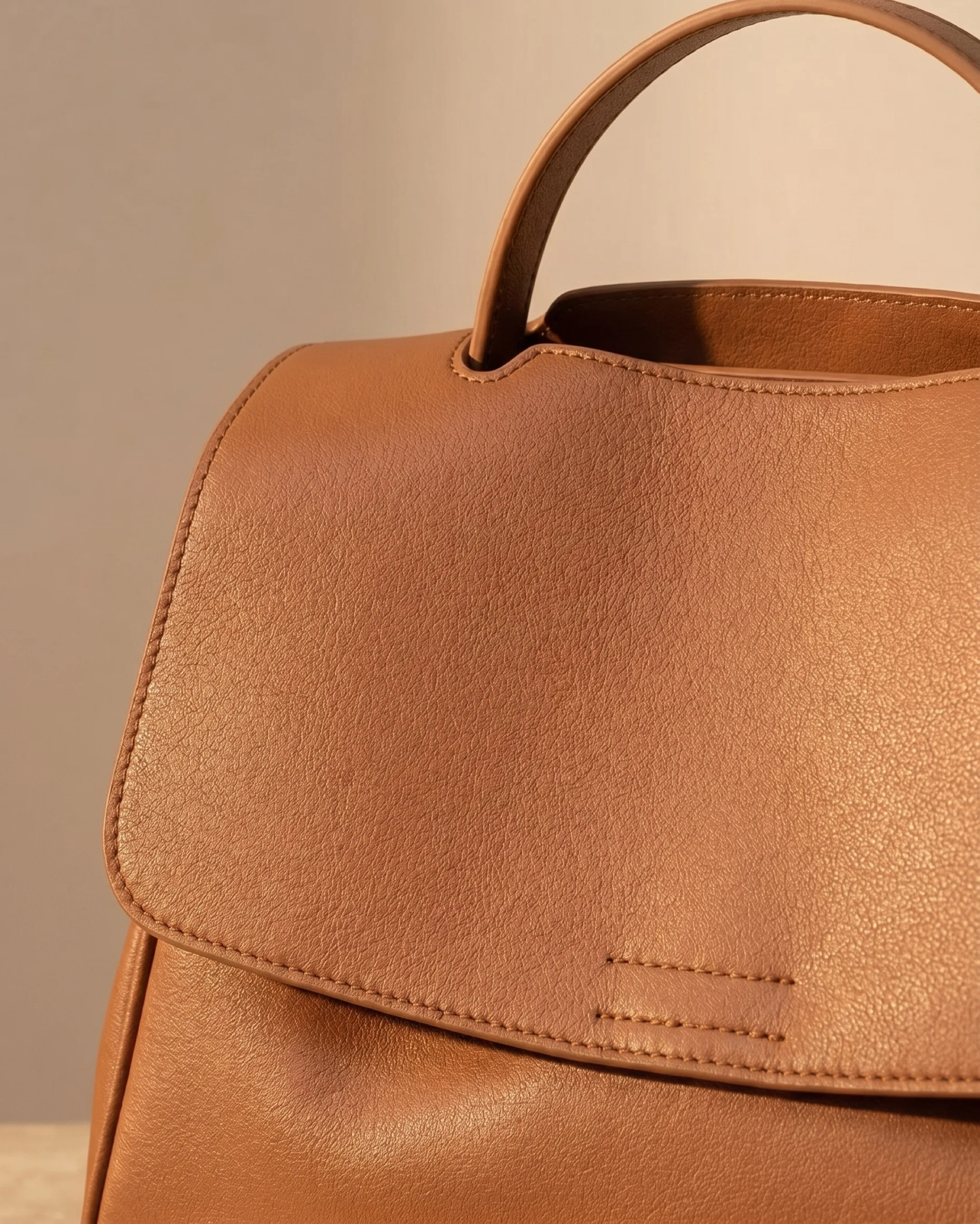 Hugo Caesar Tassi Tiberina macro of the pebbled cognac leather grain, the arched top handle and the curved flap edge with neat stitching